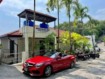 a red car parked in front of a building with motorcycles at Mountain Seaview Luxury Apartments in Kata Beach