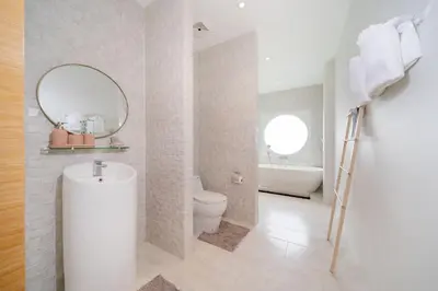 a bathroom with a sink and a toilet and a mirror at Villa Casa Koko - Luxury Modern Minimalism in Thalang