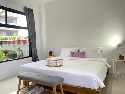a bedroom with a white bed with a chair and a window at Alleyhill Phuket - Private & Cozy Boutique in Phuket Town