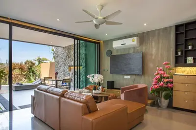 a living room with a couch and a tv at Villa Jeanne in Kamala Beach