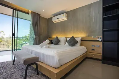 a bedroom with a large bed and a large window at Villa Jeanne in Kamala Beach
