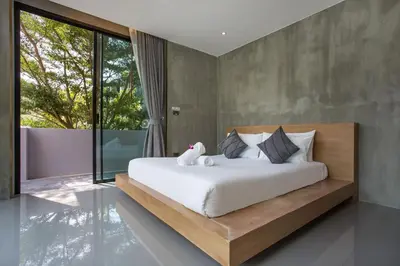 a bedroom with a large bed with white sheets and pillows at Villa Jeanne in Kamala Beach