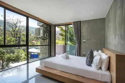 a bedroom with a white bed and large windows at Villa Jeanne in Kamala Beach