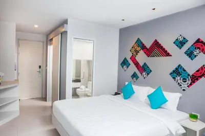 a bedroom with a large white bed with blue pillows at The Crib Patong - SHA Certified in Patong Beach