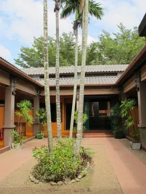 a courtyard with palm trees in front of a building at Phuket Siam Villas - SHA PLUS in Chalong