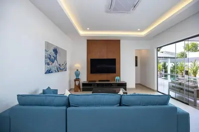 a living room with a blue couch and a tv at amazing new brand 3 bedrooms pool villa at rawai in Rawai Beach