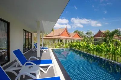 a swimming pool with chairs and a house at The Casita Phuket (SHA+) in Mai Khao Beach
