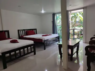 a bedroom with two beds and a table and a window at Kitty Guesthouse in Phi Phi Don