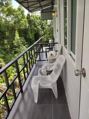 a balcony with two white chairs and a table at Kitty Guesthouse in Phi Phi Don