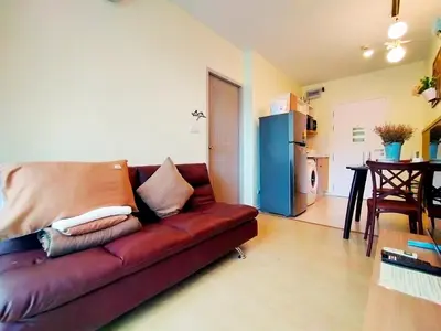 a brown couch in a living room with a kitchen at Chic & Sweet, Pool view, Prime location near beach in Phuket Town