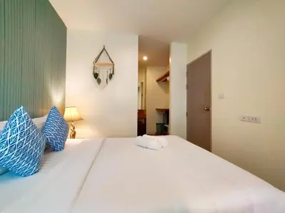 a bedroom with a bed with blue and white pillows at Chic & Sweet, Pool view, Prime location near beach in Phuket Town