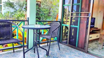 a table and two chairs on a porch with a window at Swiss Chalet Garden, Pool Resort in Krabi town