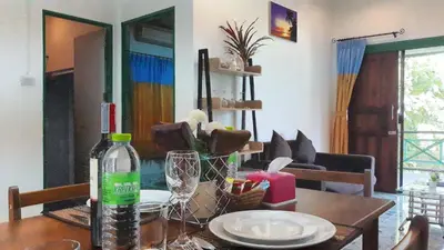a dining room table with a bottle of wine on it at Swiss Chalet Garden, Pool Resort in Krabi town