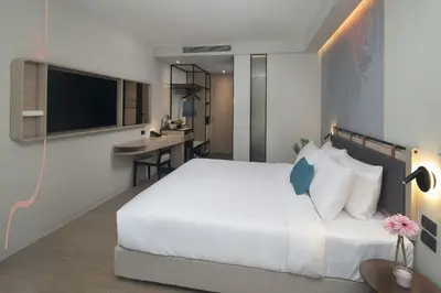 a bedroom with a large white bed and a desk at JonoX Phuket Karon Hotel in Karon Beach