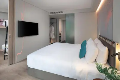 a bedroom with a white bed and a flat screen tv at JonoX Phuket Karon Hotel in Karon Beach