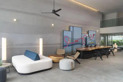 a living room with a white couch and a piano at JonoX Phuket Karon Hotel in Karon Beach