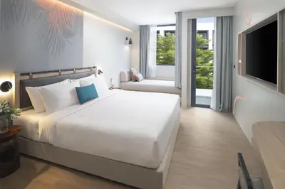 a bedroom with a large white bed and a television at JonoX Phuket Karon Hotel in Karon Beach