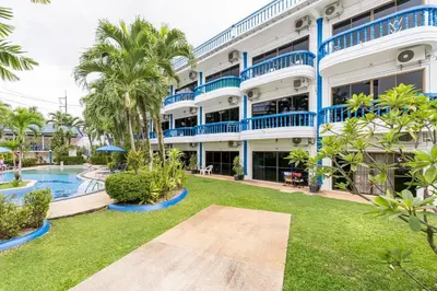 an exterior view of a building with a pool and palm trees at Kamala - The Club Residence -2 BR Pool View Residence in Kamala Beach