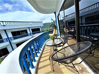 a balcony with chairs and tables on a building at Kamala - The Club Residence -2 BR Pool View Residence in Kamala Beach