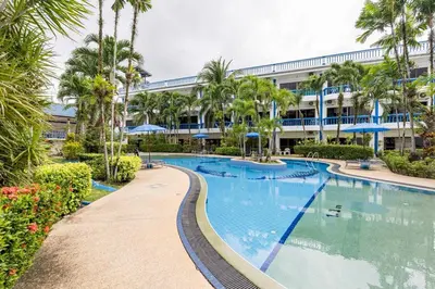 a large swimming pool with palm trees in front of a building at Kamala - The Club Residence -2 BR Pool View Residence in Kamala Beach