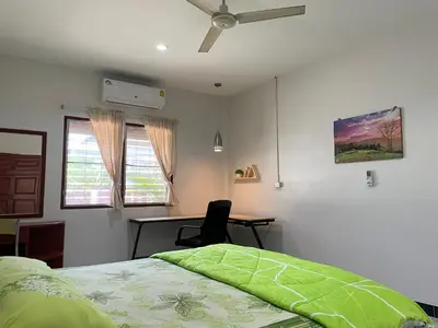 a bedroom with a bed and a desk and a ceiling fan at 1BR Cozy House, Bangtao Beach in Ban Thalat Choeng Thale