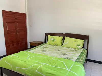 a bed with green sheets and pillows in a bedroom at 1BR Cozy House, Bangtao Beach in Ban Thalat Choeng Thale