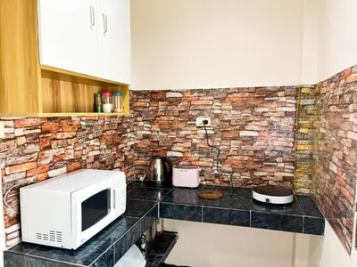 a kitchen with a microwave and a brick wall at 1BR Cozy House, Bangtao Beach in Ban Thalat Choeng Thale