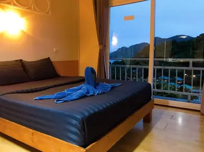 a bed with a person laying on it in front of a window at Blue View House Phi Phi in Phi Phi Don