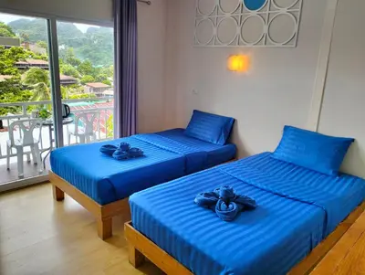 two beds with blue sheets in a room with a balcony at Blue View House Phi Phi in Phi Phi Don