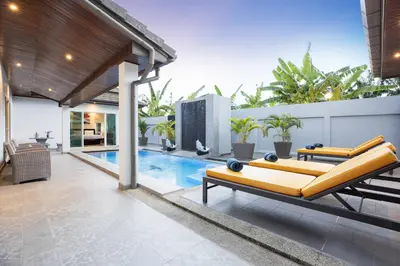 an outdoor living room with a yellow couch and a pool at 3BR Villa Marine with Private Pool, Waterfalls in NaiHarn Beach in Rawai Beach