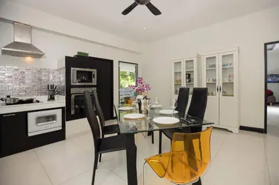 a kitchen with a glass table and black chairs at 3BR Villa Marine with Private Pool, Waterfalls in NaiHarn Beach in Rawai Beach