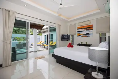 a bedroom with a bed and a view of the ocean at 3BR Villa Marine with Private Pool, Waterfalls in NaiHarn Beach in Rawai Beach