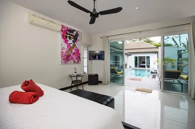 a bedroom with a white bed and a living room at 3BR Villa Marine with Private Pool, Waterfalls in NaiHarn Beach in Rawai Beach