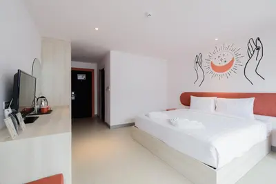a white bedroom with a bed and a tv at Moon Budget Hotel in Ao Nang Beach