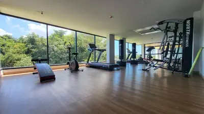 a gym with several treadmills and machines in a room with windows at VIP Great Hill Phuket Airport in Phuket Town
