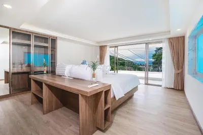 a bedroom with a bed and a desk and windows at seaview villa private swimming pool in Karon Beach