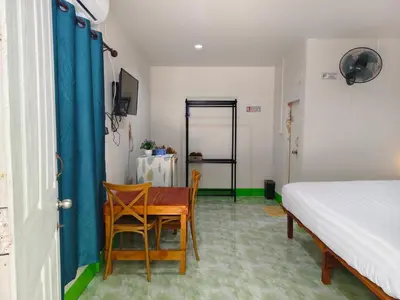 a bedroom with a bed and a table and chairs at TR Bungalow in Ban Tha Rua