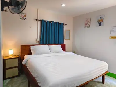 a bedroom with a large bed with a blue curtain at TR Bungalow in Ban Tha Rua