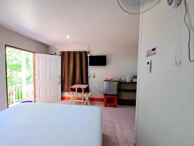 a bedroom with a bed and a desk and a table at TR Bungalow in Ban Tha Rua