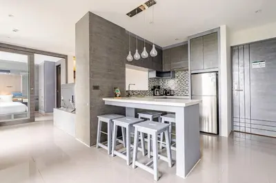 a kitchen with a white counter and stools in it at CityGate by Villacarte in Kamala Beach