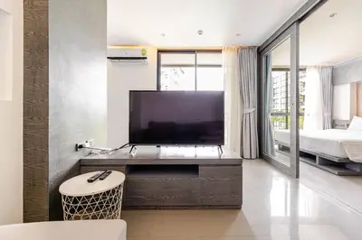 a living room with a large television and a bedroom at CityGate by Villacarte in Kamala Beach