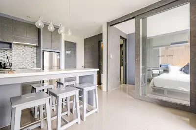 a kitchen with a bar with stools and a bedroom at CityGate by Villacarte in Kamala Beach