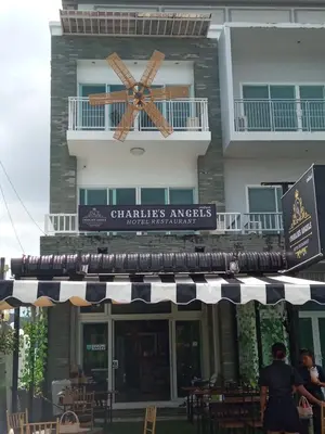 a building with a sign for a restaurant with a clock on it at Charlie's Angels Hotel Restaurant in Rawai Beach