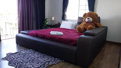 a large teddy bear sitting on top of a bed at Charlie's Angels Hotel Restaurant in Rawai Beach