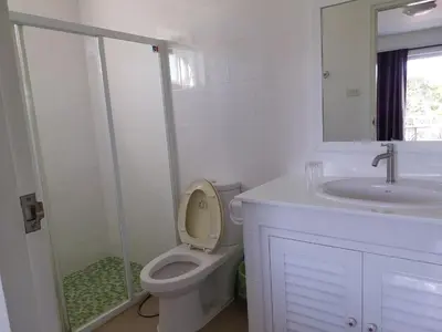 a white bathroom with a toilet and a sink at Charlie's Angels Hotel Restaurant in Rawai Beach