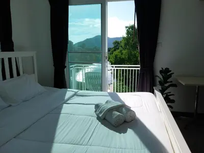 a bedroom with a white bed with a large window at Charlie's Angels Hotel Restaurant in Rawai Beach