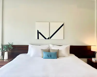 a bedroom with a large white bed with two pillows at The Langstan Suites in Nai Harn Beach