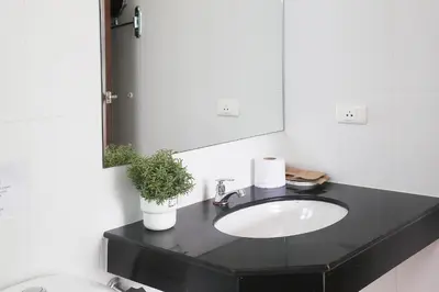 a bathroom with a sink and a mirror at The Langstan Suites in Nai Harn Beach