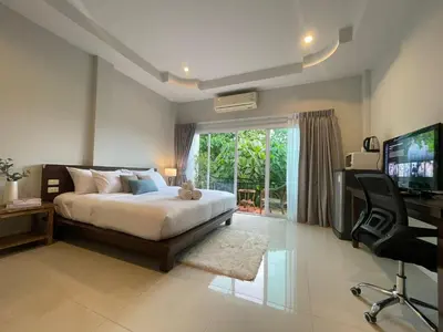 a bedroom with a bed and a television and a desk at The Langstan Suites in Nai Harn Beach