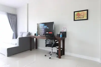a desk with a computer and a chair in a room at The Langstan Suites in Nai Harn Beach
